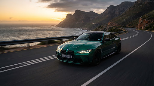 2025 BMW M4 Competition carving through coastal curves on Chapman's Peak at sunset